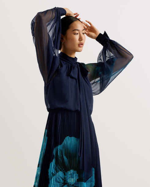 MANAMI-Dresses-The MANAMI maxi dress exudes glamour from head to toe, starting with a classic bow tie around the neck and ending with a fine pleated skirt. Floral details are printed on this piece to add an understated splash of colour, finished out with sheer bishop sleeves and a full hem to create plenty of swish. Maxi dress Large scale floral print details High neck with pussybow tie Sheer long bishop sleeves Pleated A-line skirt Front split Concealed zip fastening Chae is 5'9.5" / 1.77m and wears a Ted